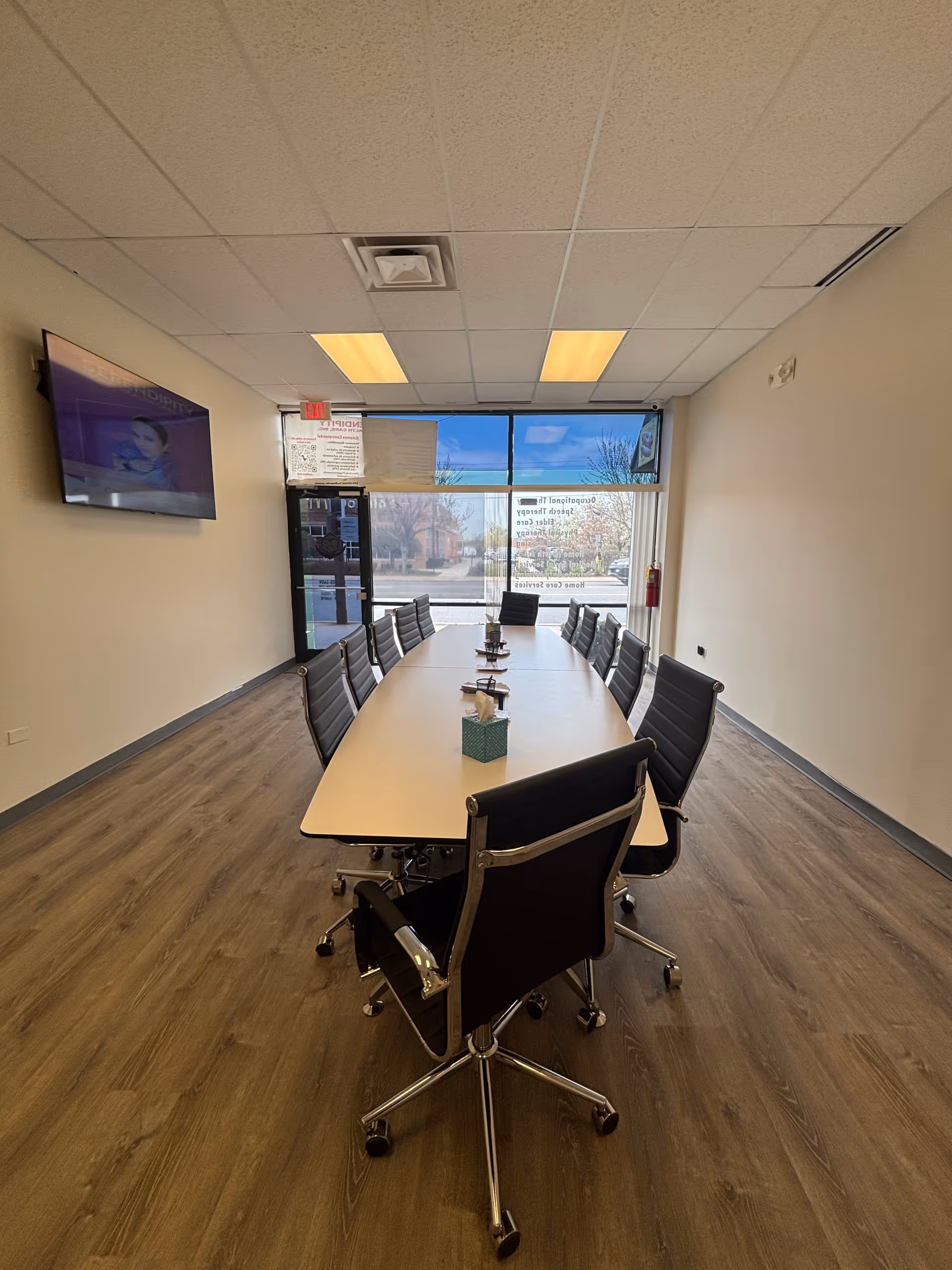 Long conference table with black rolling chairs in a bright interior meeting room.