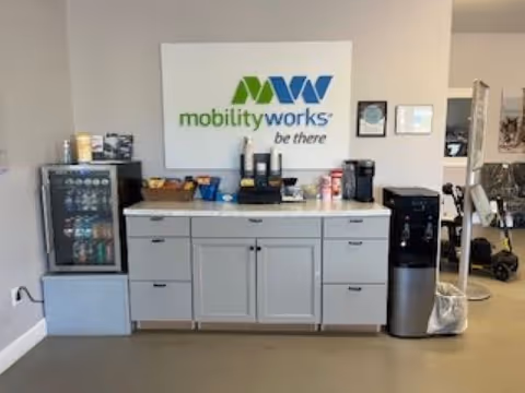 Indoor reception area with a coffee station, vending cooler, and MobilityWorks sign.