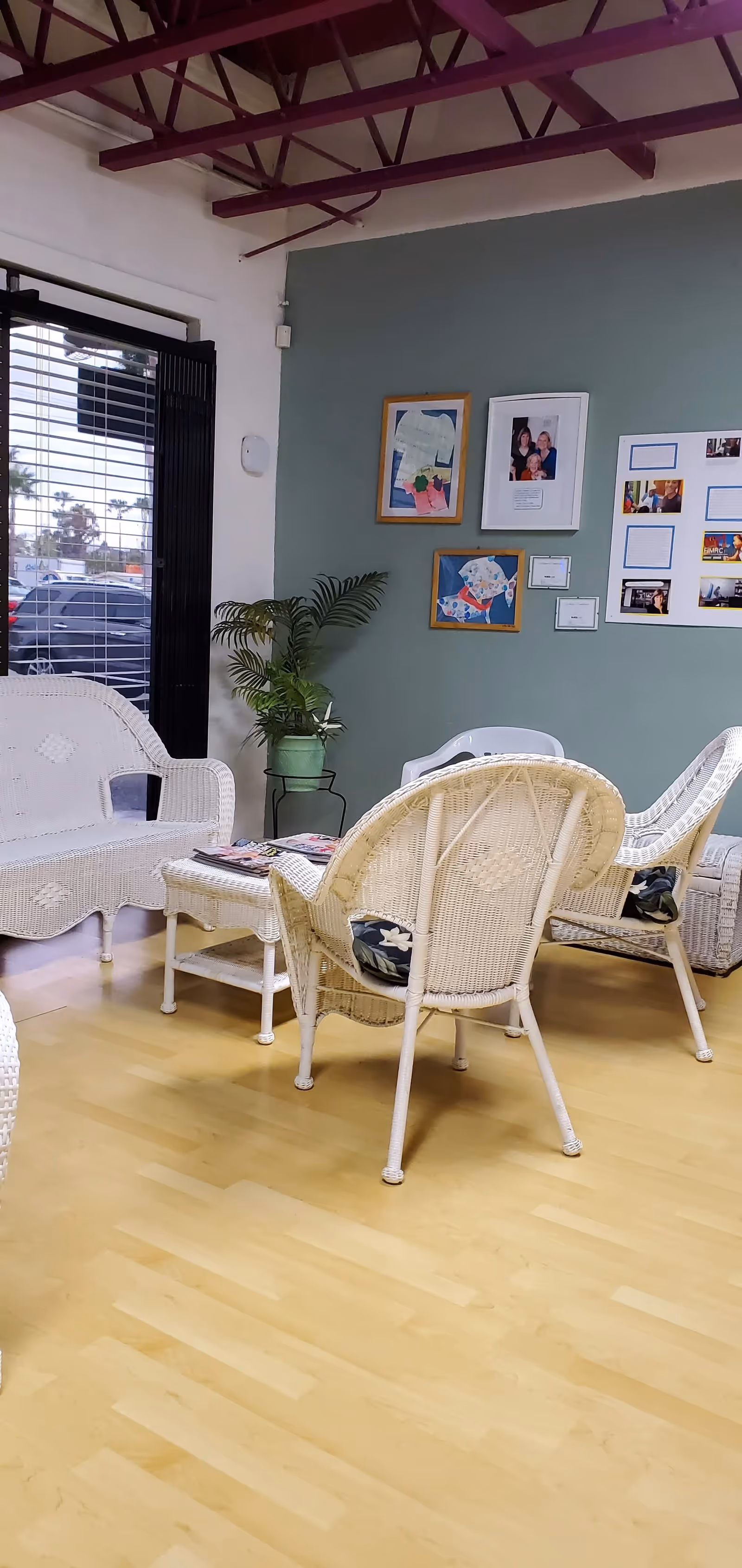 Wicker seating and a coffee table in a bright lounge with wall art and a plant.
