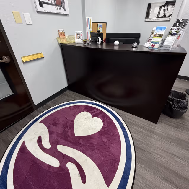 Reception desk in a senior care facility lobby with brochures and a purple heart rug.