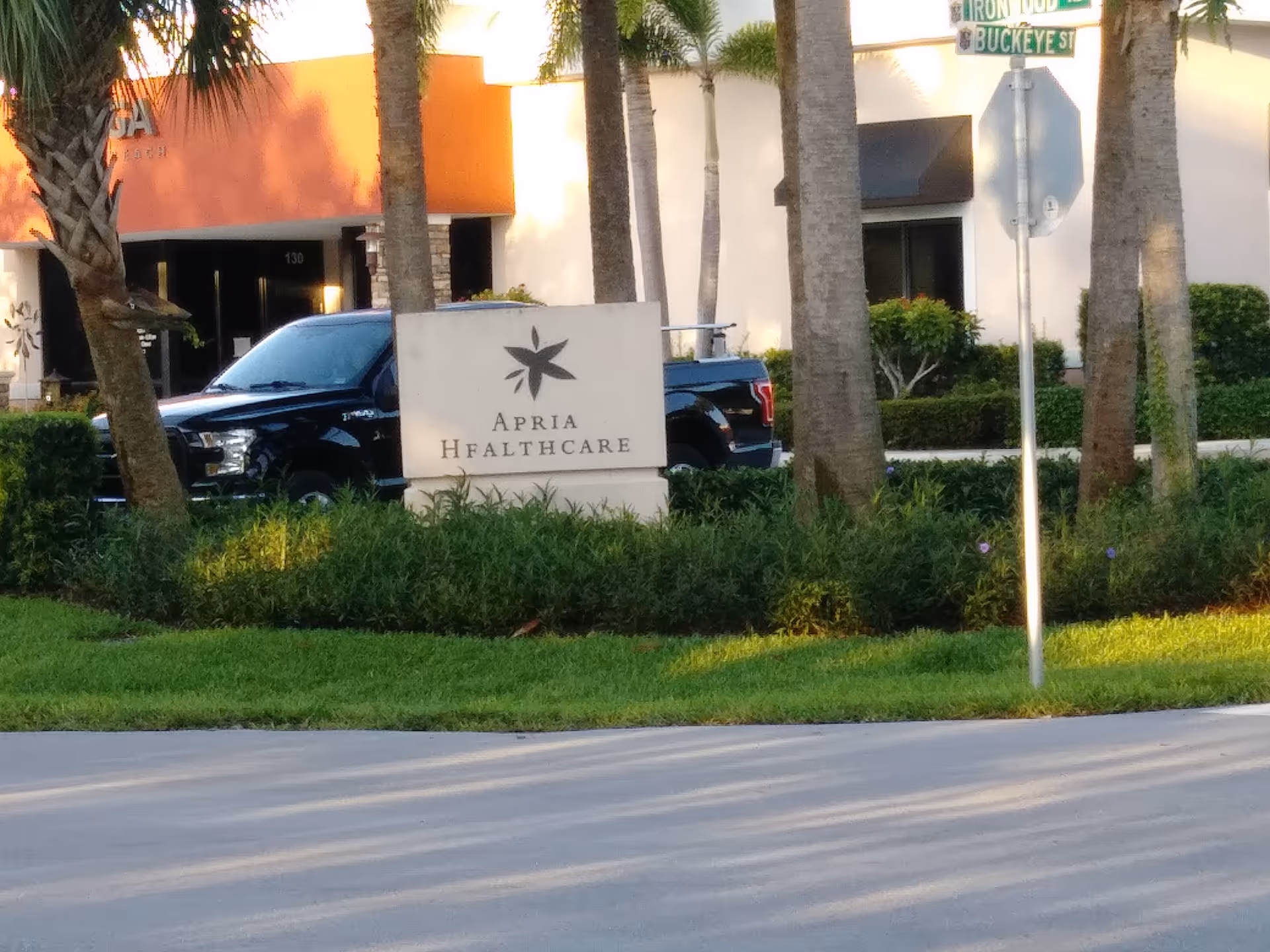 Exterior view of Apria Healthcare facility with a sign and palm trees.