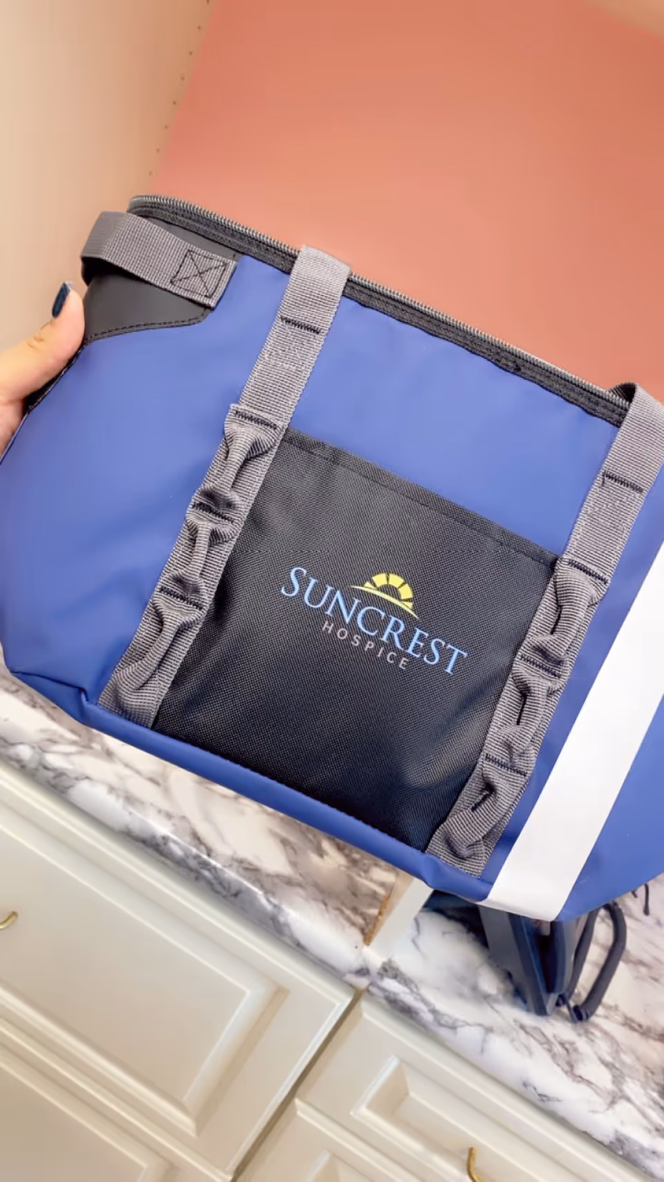 Blue Suncrest Hospice tote bag on marble kitchen counter inside a facility.