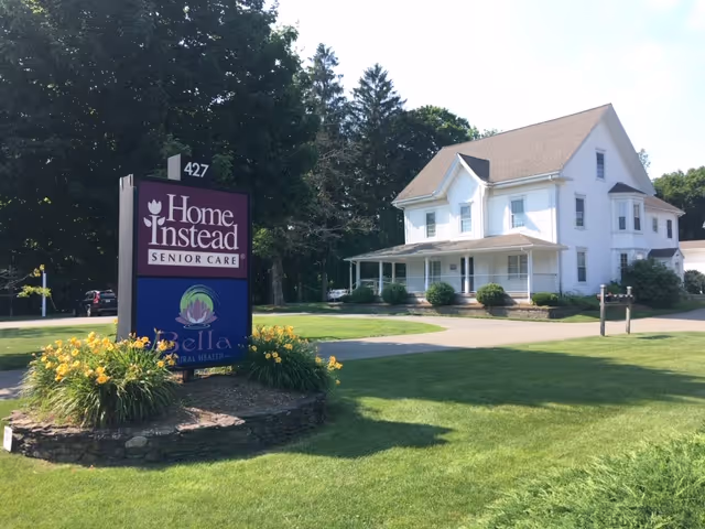 White two-story senior care building with a Home Instead sign in a well-kept lawn
