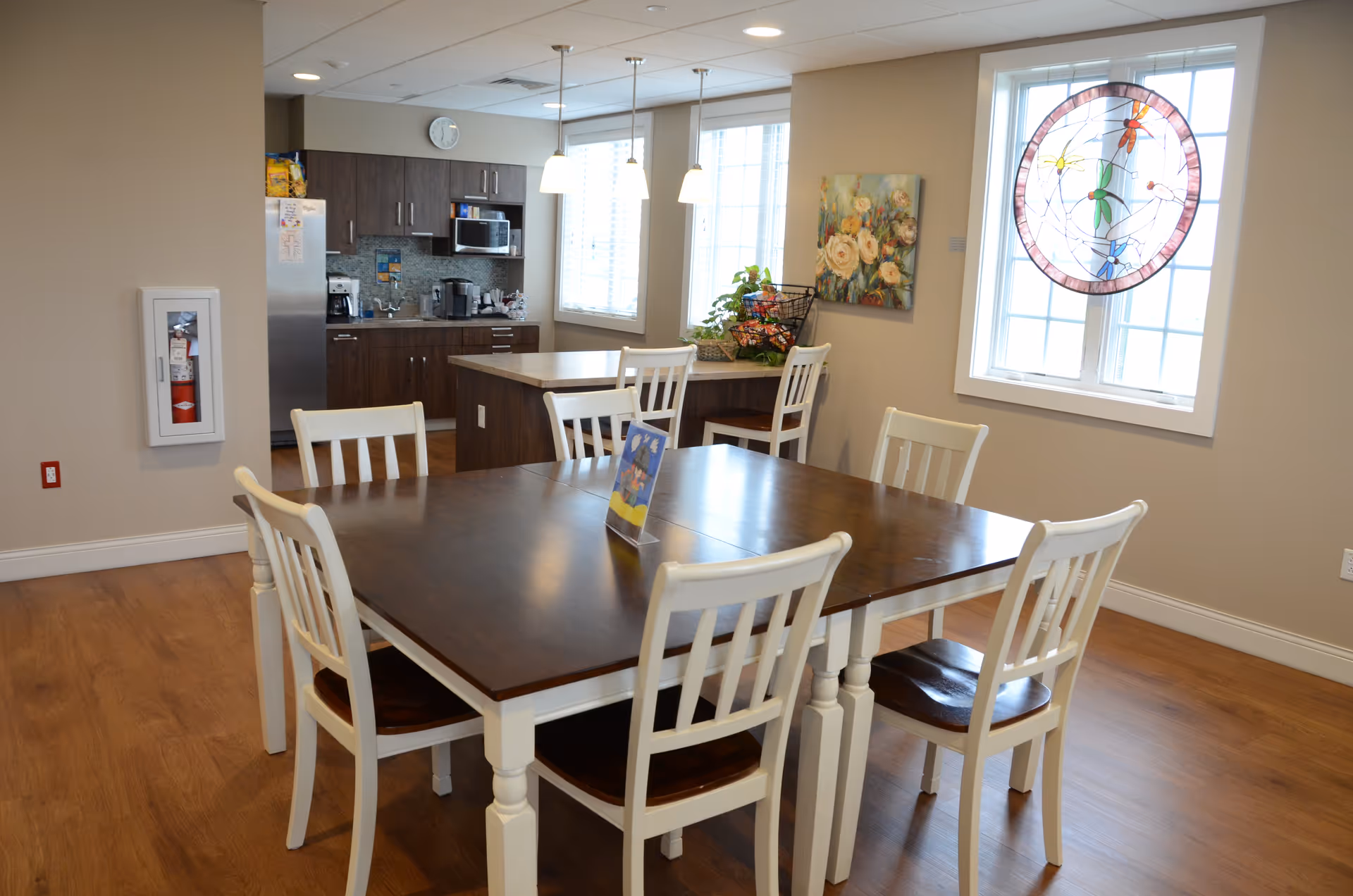 A spacious dining room in a senior living facility with a large wooden table and chairs.