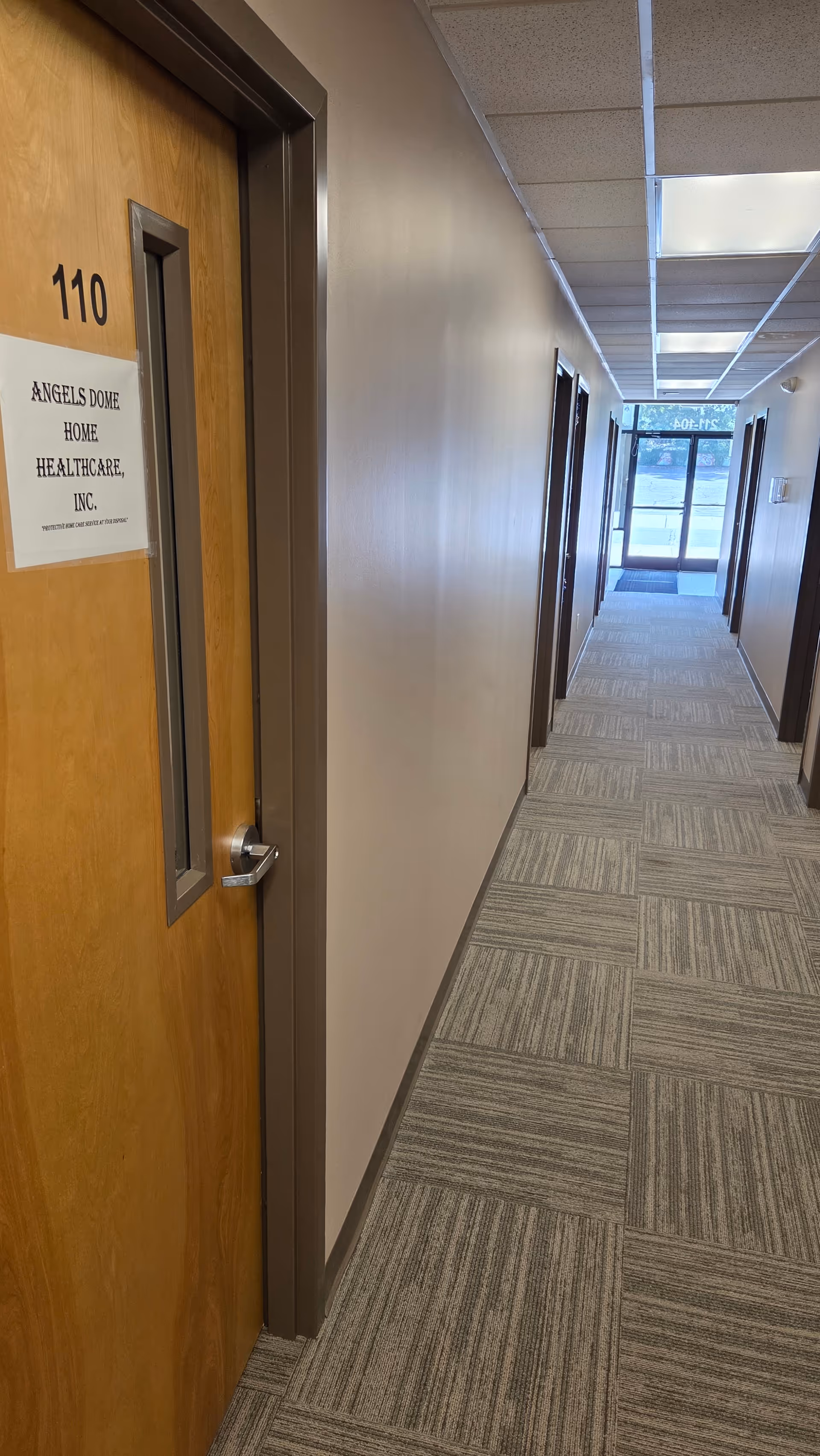 Interior hallway at Angels Dome Home Healthcare, Inc., with numbered doors and patterned carpet.