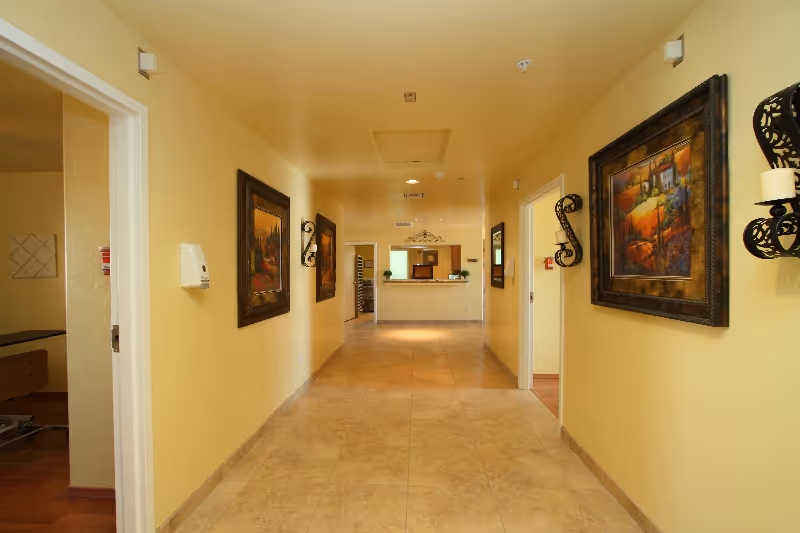 Wide hallway in a senior living facility with wall art and a reception desk