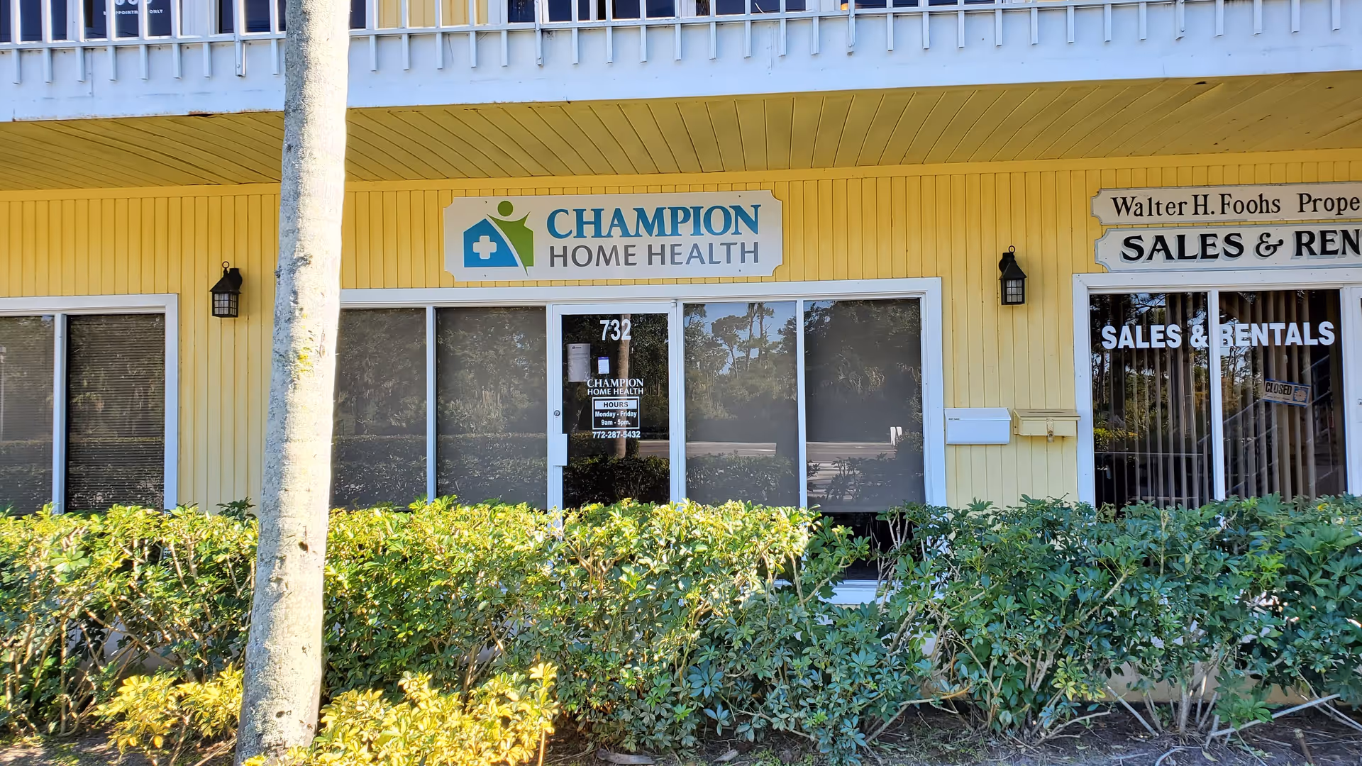 Yellow storefront for Champion Home Health Care with shrubs and large windows.