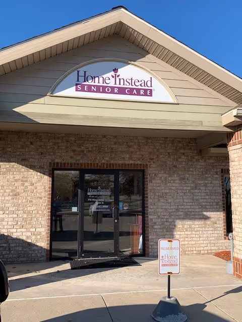 Front exterior of Home Instead Senior Care building with sign above glass doors.