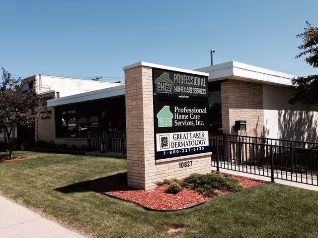 Exterior view of a senior care facility with a brick sign and entrance.