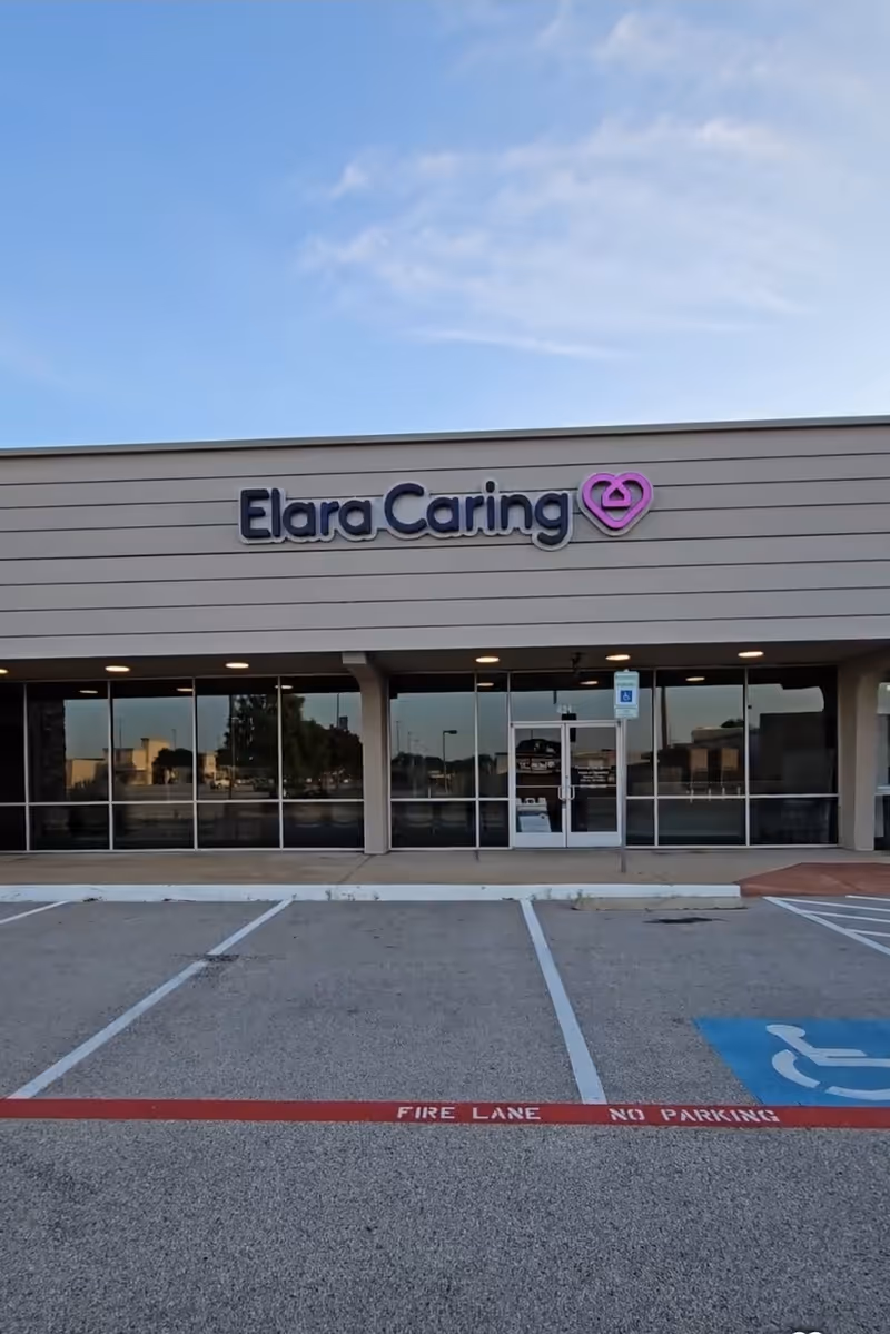 Exterior facade of Elara Caring facility featuring signage and glass entrance.