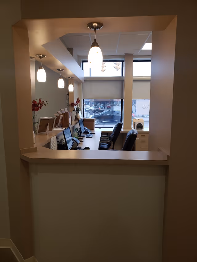 Front desk area with computers, chairs, and pendant lights inside a clinic