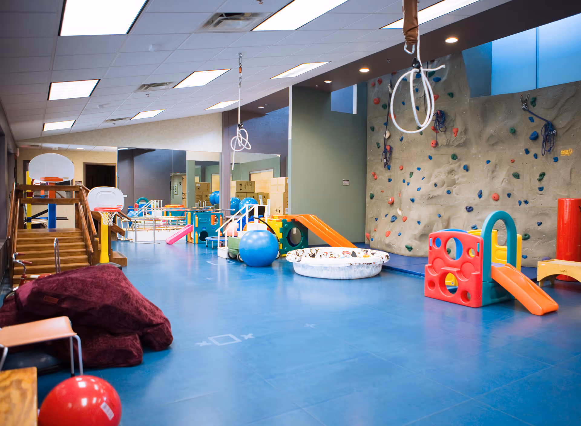 Indoor playroom with a climbing wall, slides, and colorful soft play equipment.