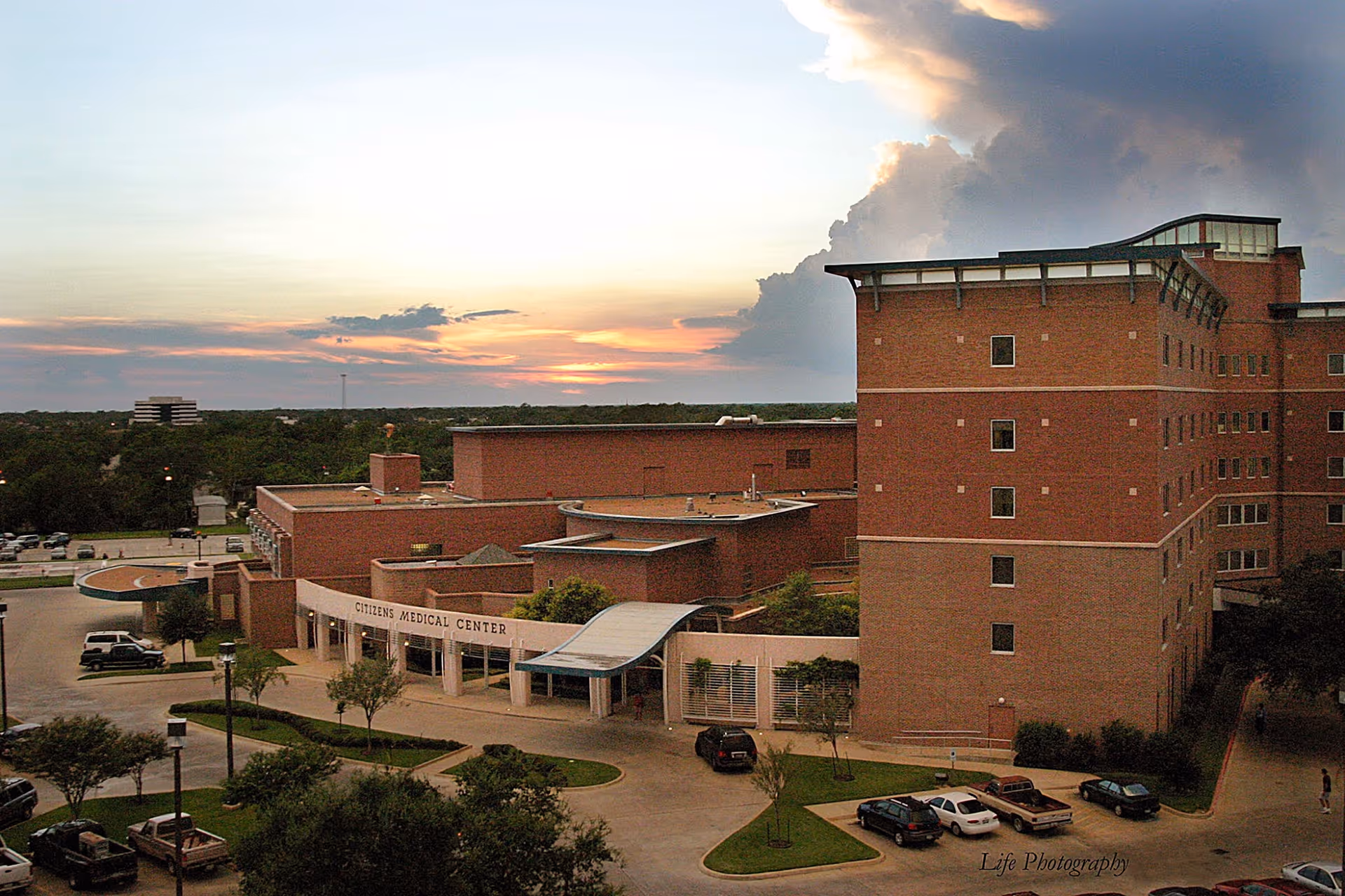 Exterior view of Citizens Medical Center building at sunset with parked cars.