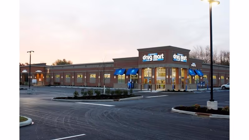 Exterior view of a Discount Drug Mart store with blue awnings and a parking lot.