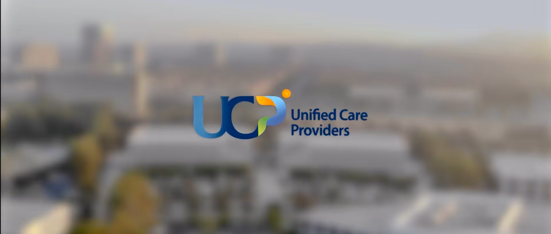 Blurred aerial view with Unified Care Providers logo centered over a campus.