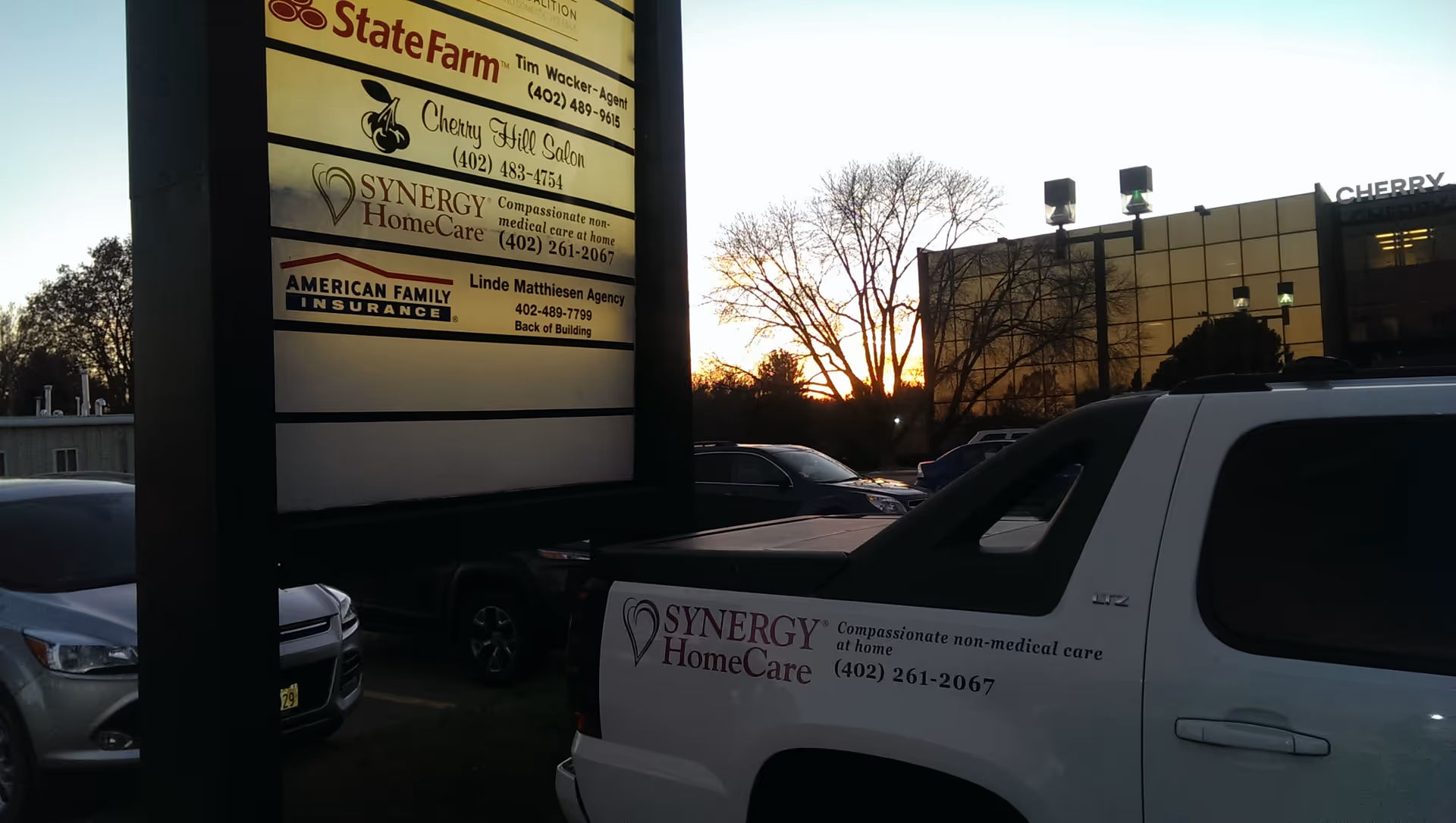 Exterior scene with Synergy HomeCare sign and branded white van outside a building at dusk.