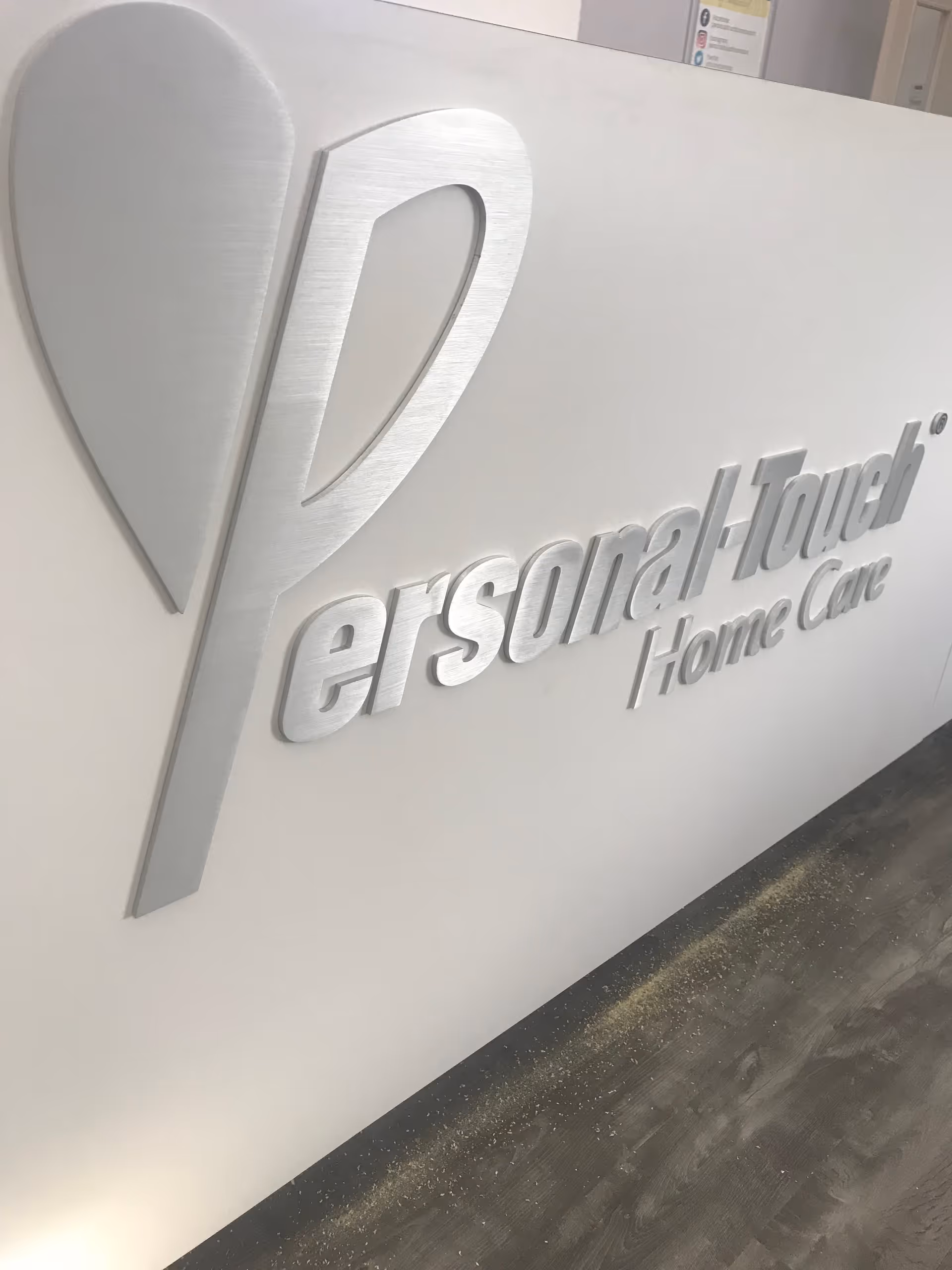 Interior wall featuring a large three-dimensional Personal-Touch Home Care logo sign.