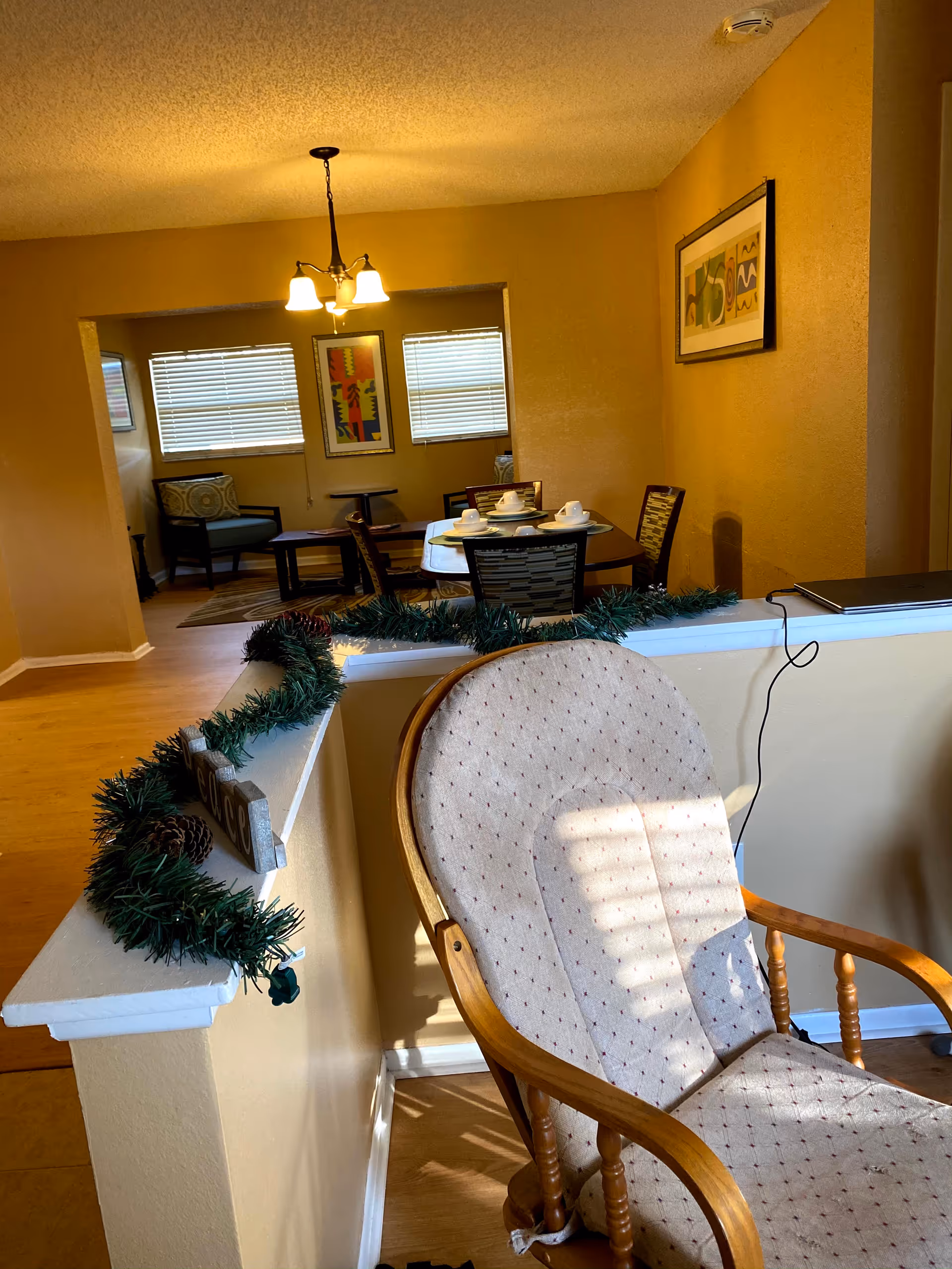 View of a yellow-walled dining area with a table set for meals and surrounding chairs.