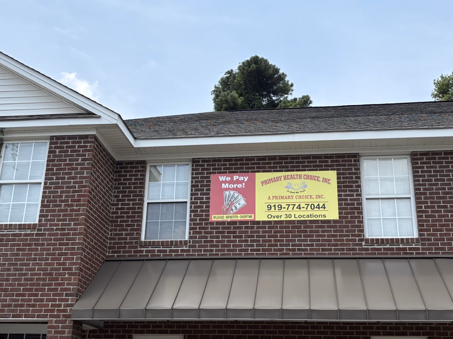 Brick building exterior with a yellow banner advertising Primary Health Choice on the second floor.