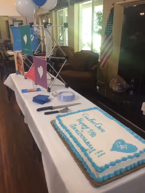Cake celebrating ComForCare anniversary on a decorated table in a facility lobby.