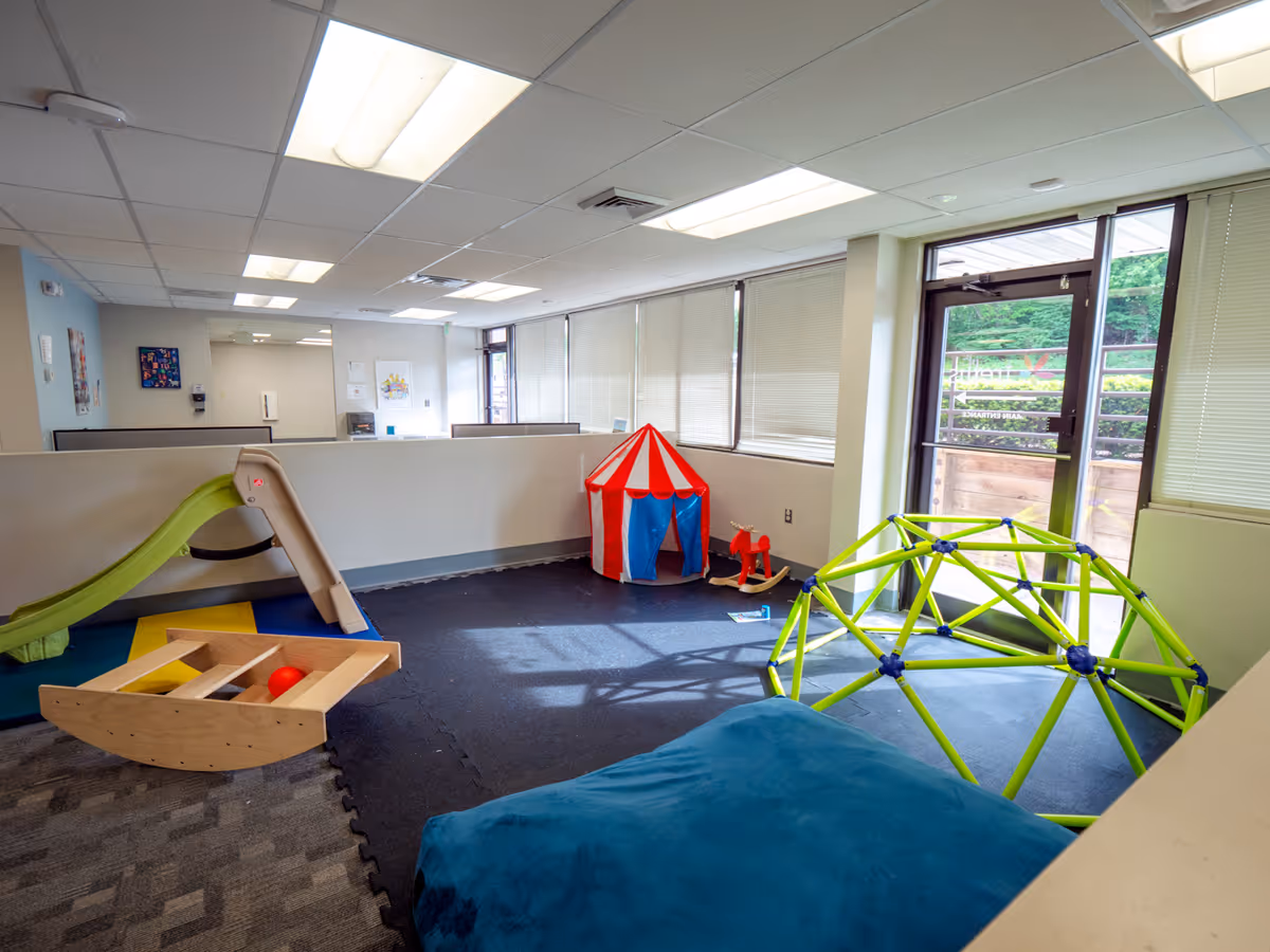 Colorful children's play area with slide, tent, and climbing dome inside a bright facility.