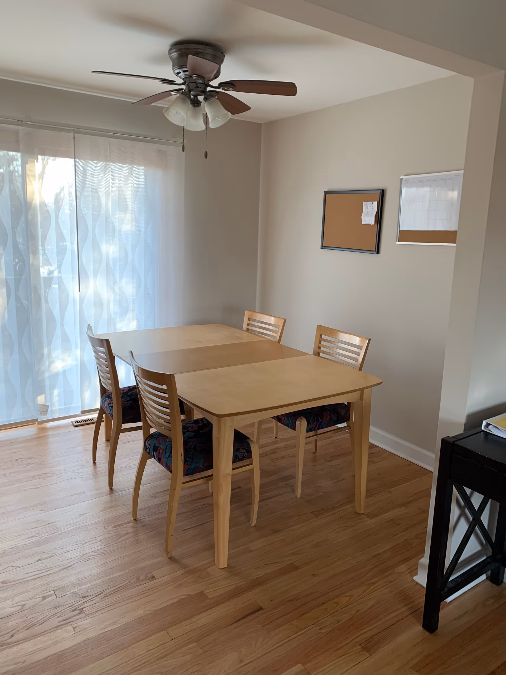 Light-filled dining area with a wooden table and chairs near sliding glass doors.