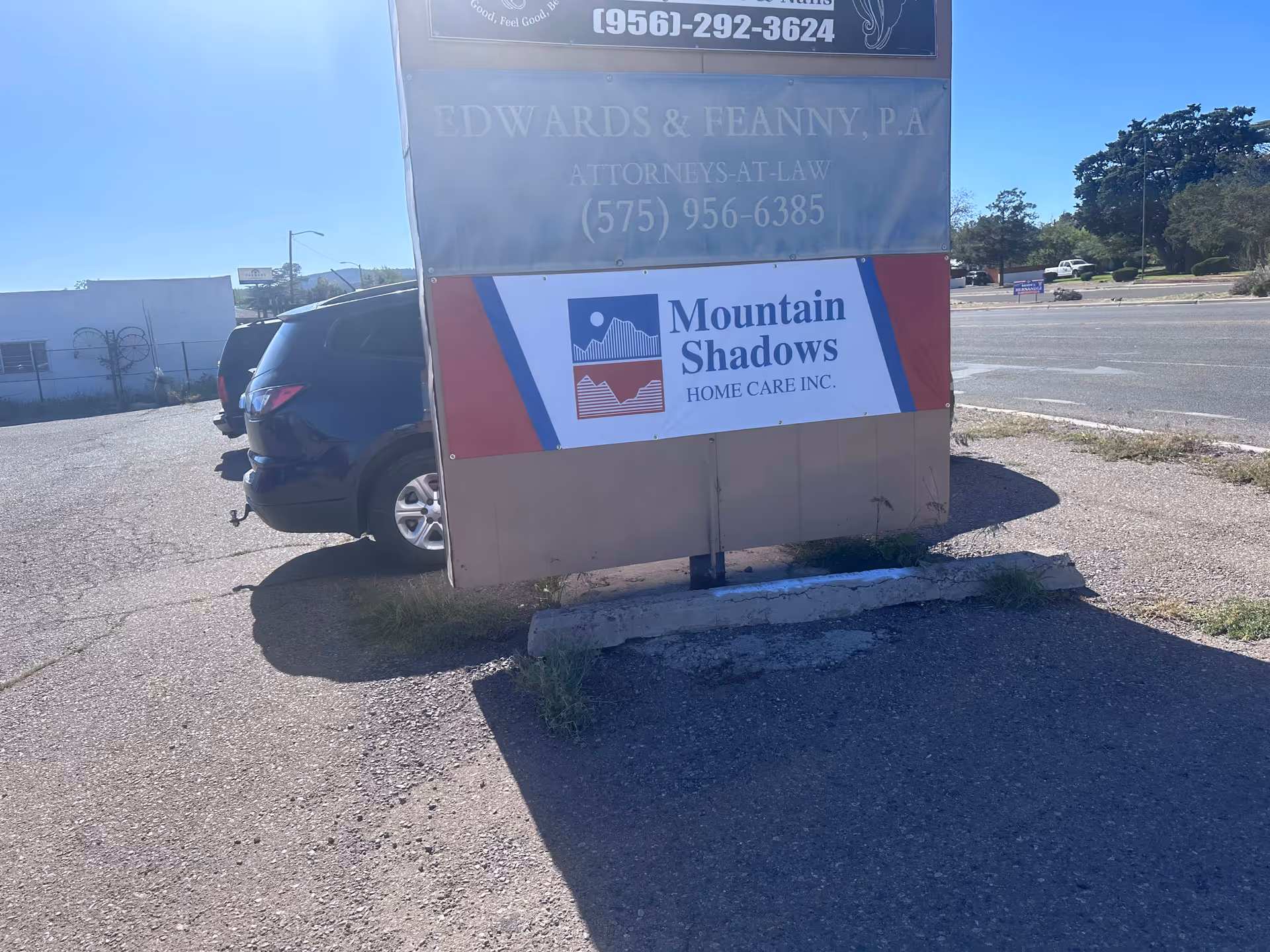 A roadside sign for Mountain Shadows Home Care Inc. with a parked car beside it.