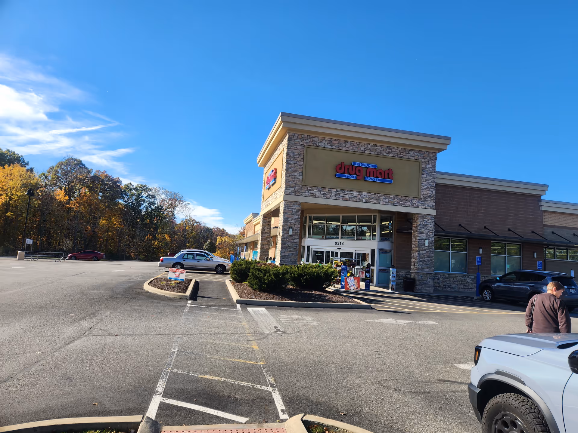 Exterior view of Discount Drug Mart storefront with parking lot and fall trees.