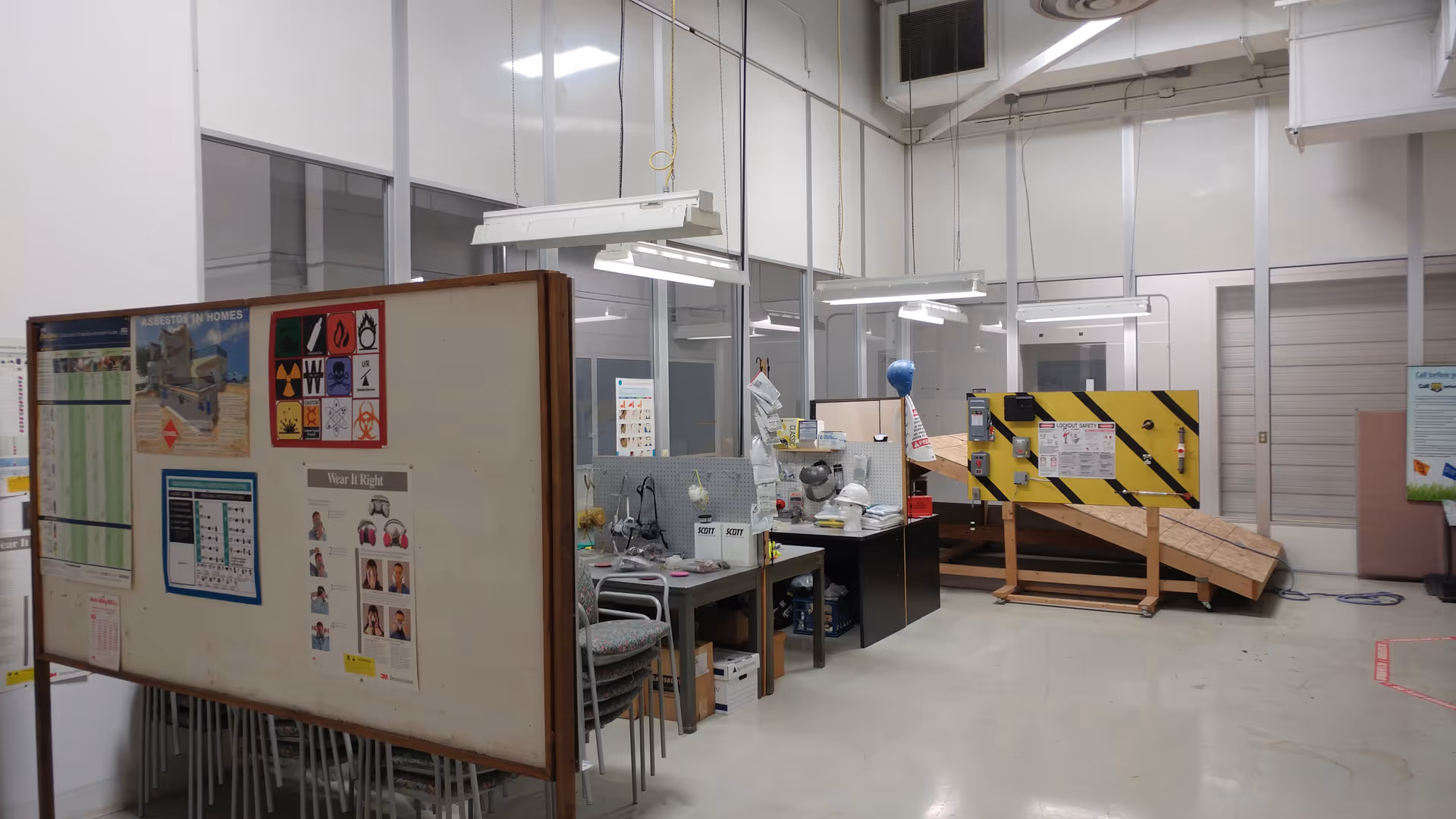 Industrial workshop interior with desks, bulletin boards, and a wooden ramp.