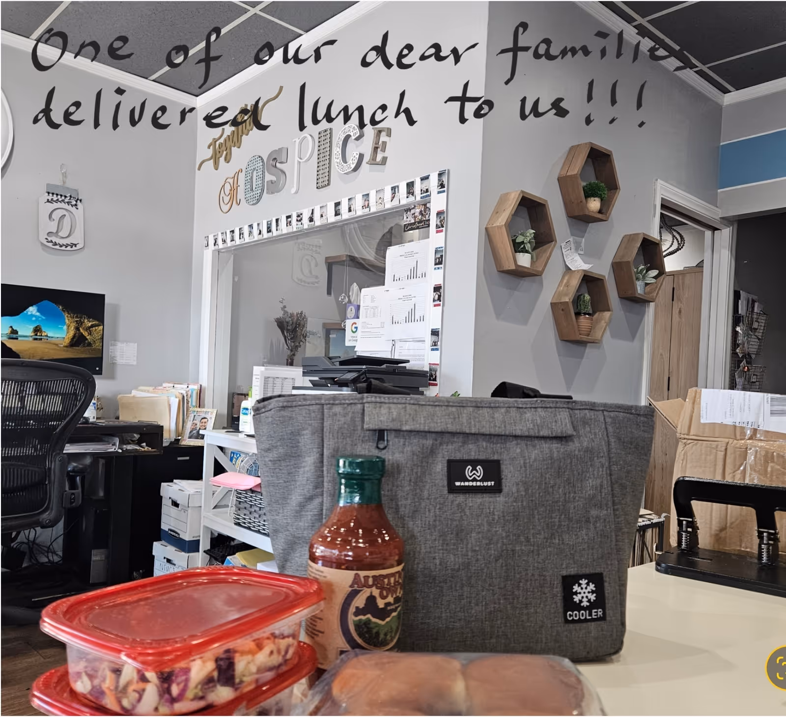 Office reception area with desk, cooler bag, sauce bottle, and hexagonal wall shelves.