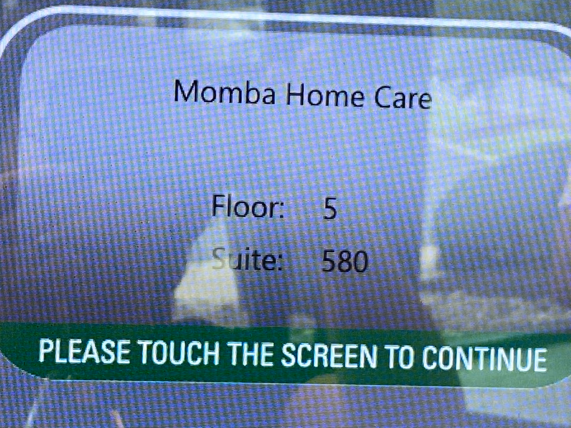 Display shows Momba Home Care, Floor 5, Suite 580, and 'Please touch the screen to continue'.
