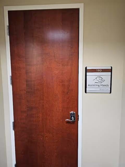 Wooden interior door beside wall sign for Assisting Hands Home Care.