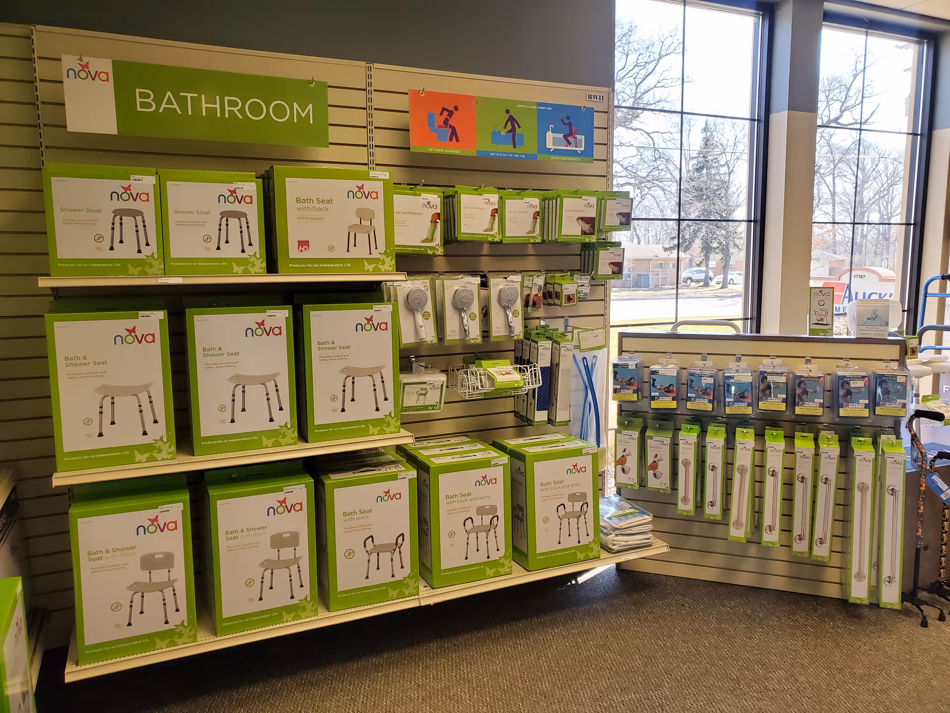 Interior showroom displaying green-packaged bathroom aids on wall shelves by windows