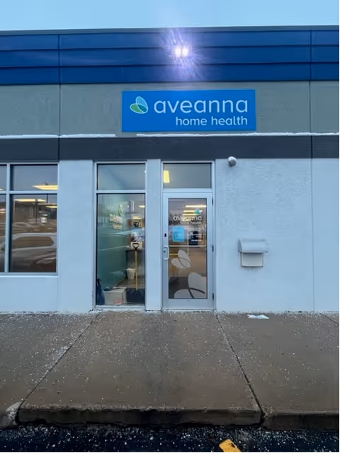 Exterior view of Aveanna Home Health storefront with glass door and blue sign