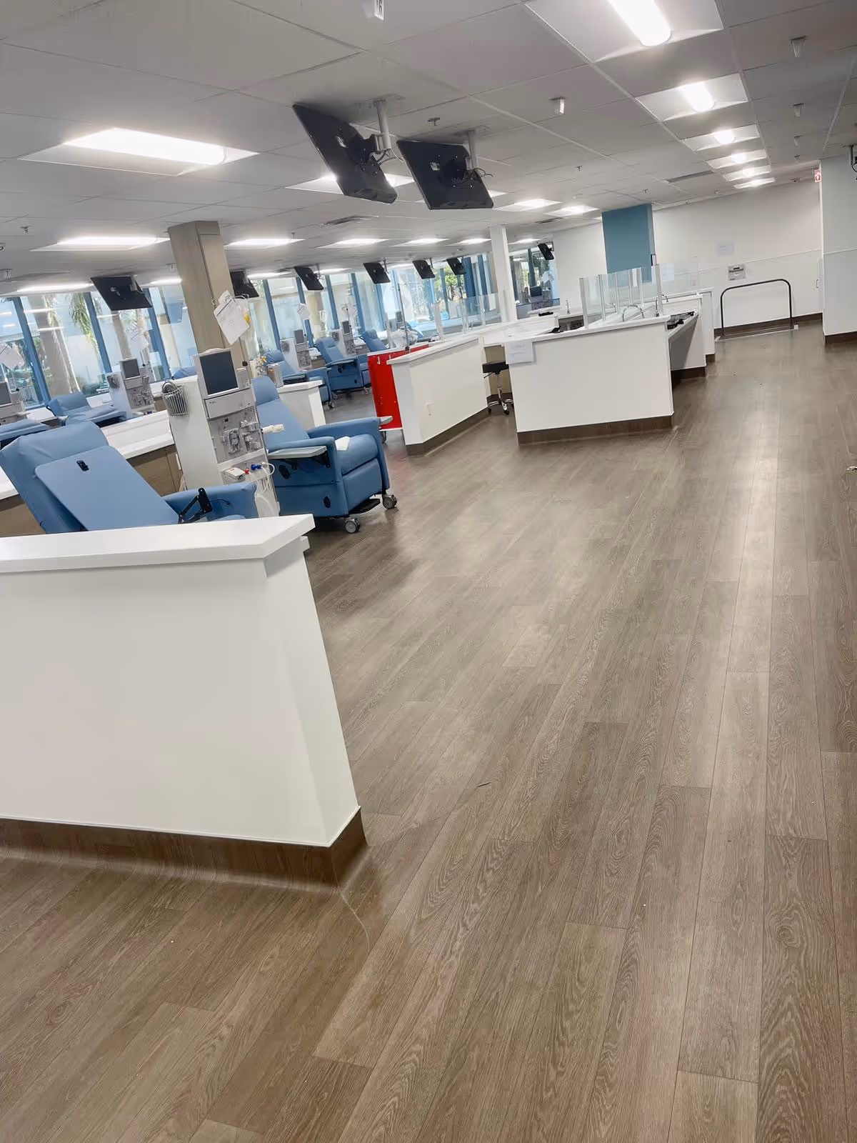 Interior of a dialysis center showing rows of blue reclining chairs and workstations.