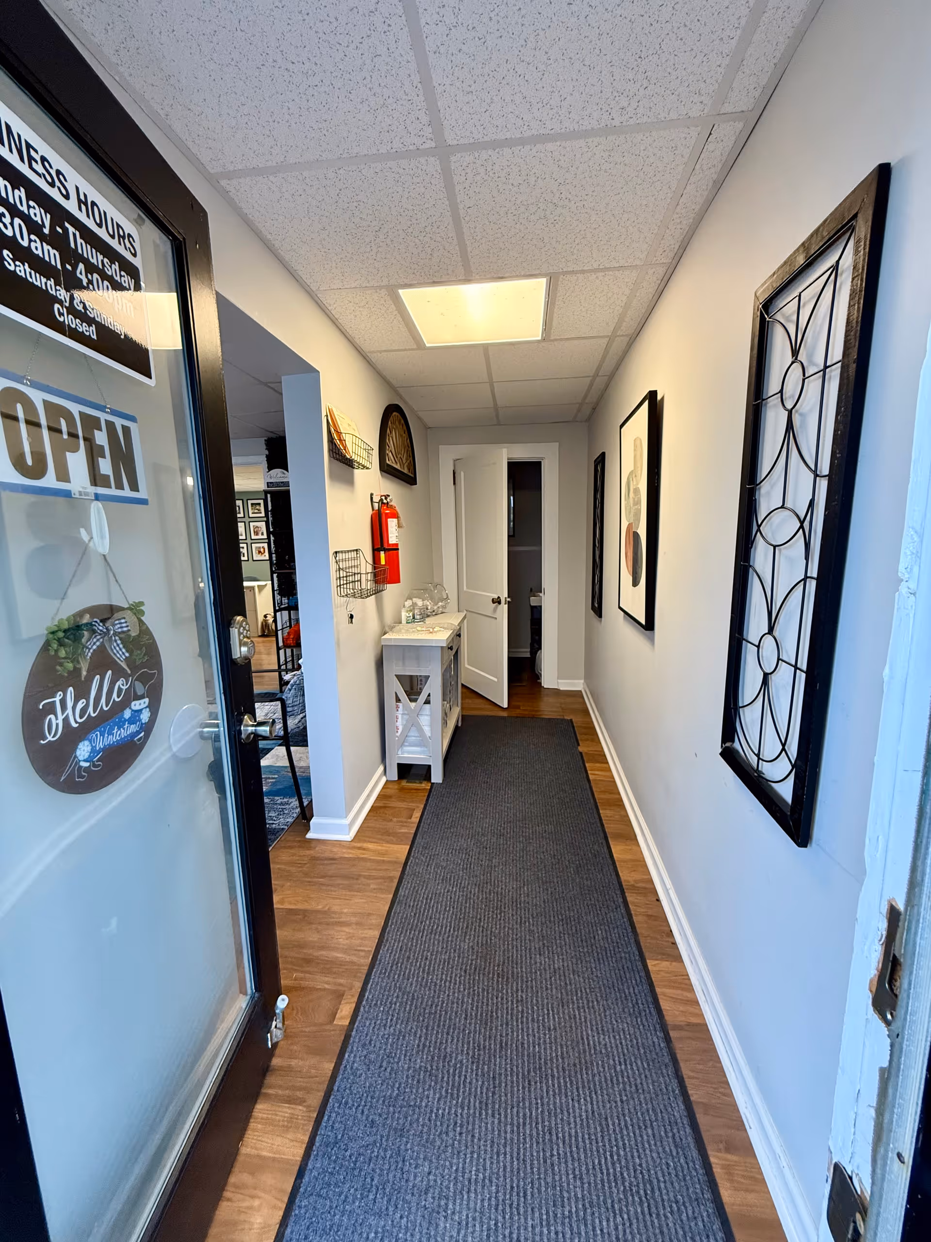 Interior hallway at Beyond Care facility with open door, wall art, and a rug.