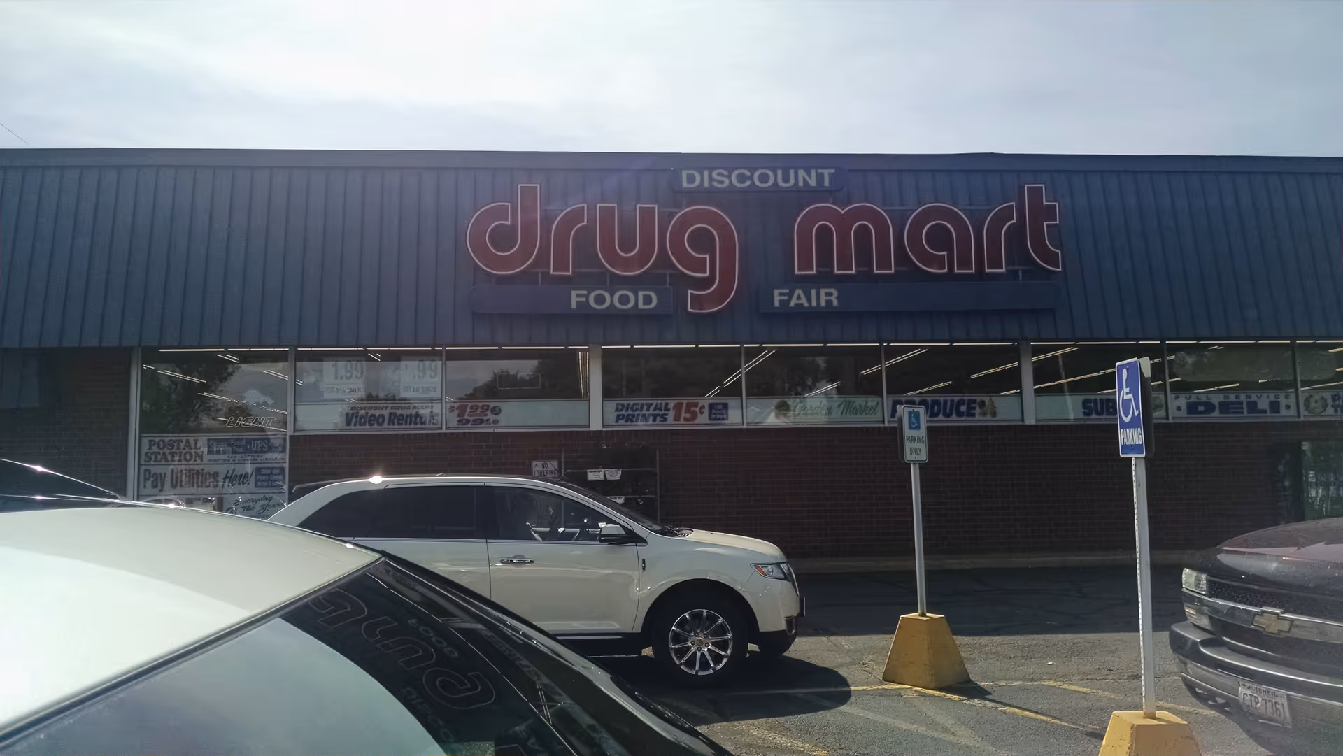 Front view of Discount Drug Mart storefront with parked cars outside.