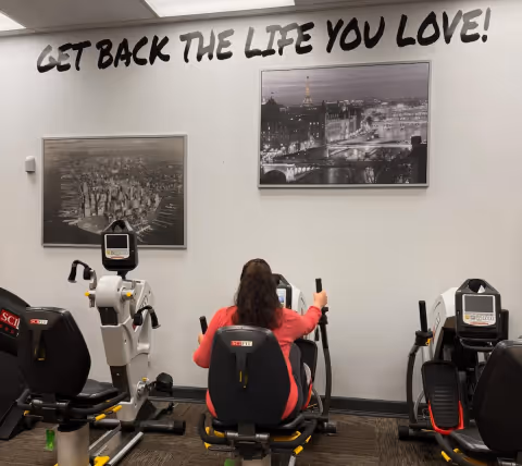 A physical therapy gym with exercise bikes and a person using one.