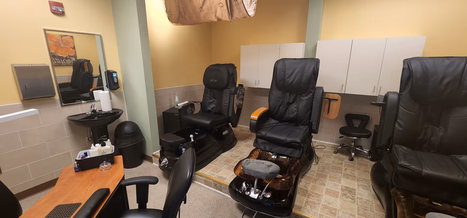 Treatment room with reclining chairs, sinks, a mirror, and white cabinets in a senior care facility.
