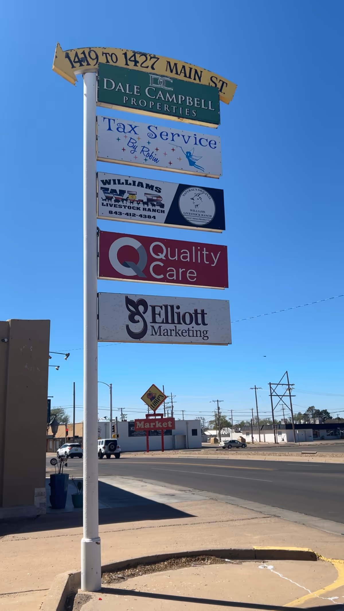 Tall outdoor signpost with multiple business signs, including Quality Care, against blue sky.