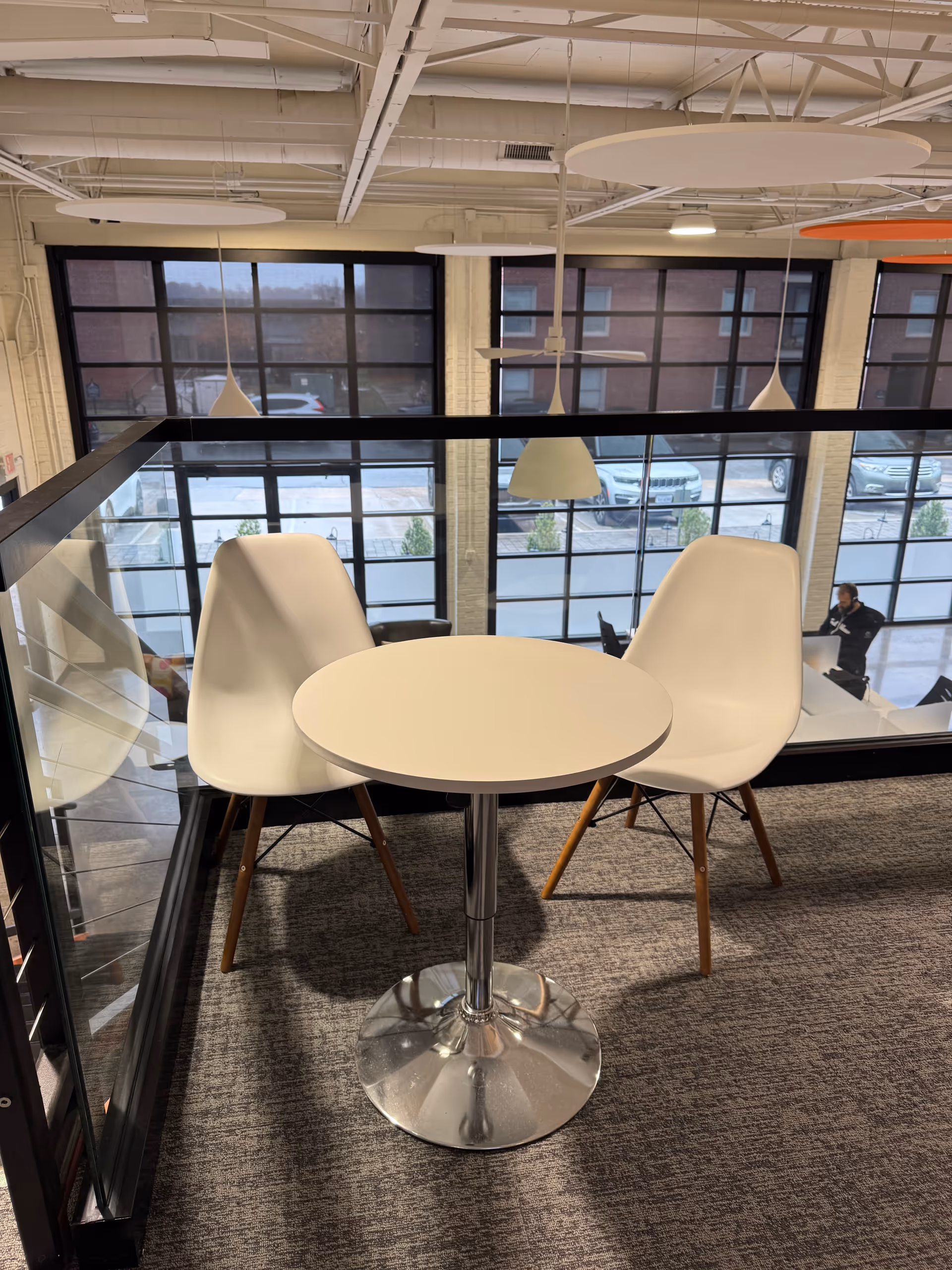 Modern interior seating area with a round table and white chairs by large windows.