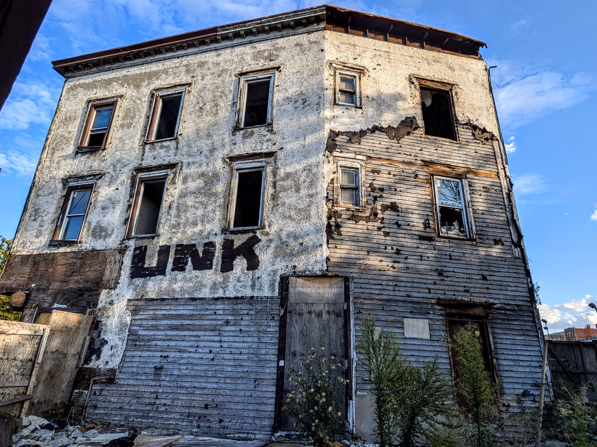 A deteriorated, abandoned two-story building with peeling siding and broken windows.
