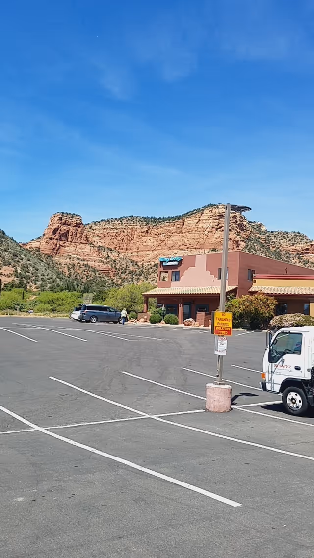 Exterior view of a Compassus facility with a parking lot and red rock hills behind.