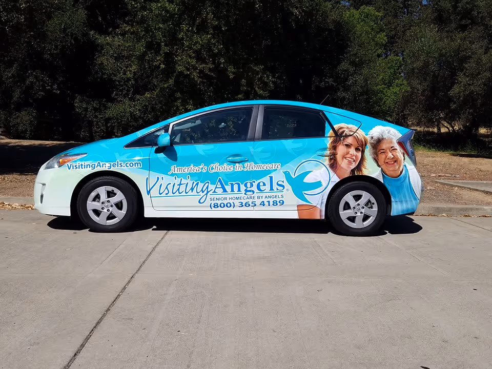 Blue and white Visiting Angels senior home care van parked on a sunny street.