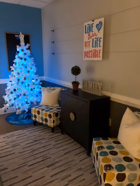 Interior living area with a blue-lit white Christmas tree and patterned seating.
