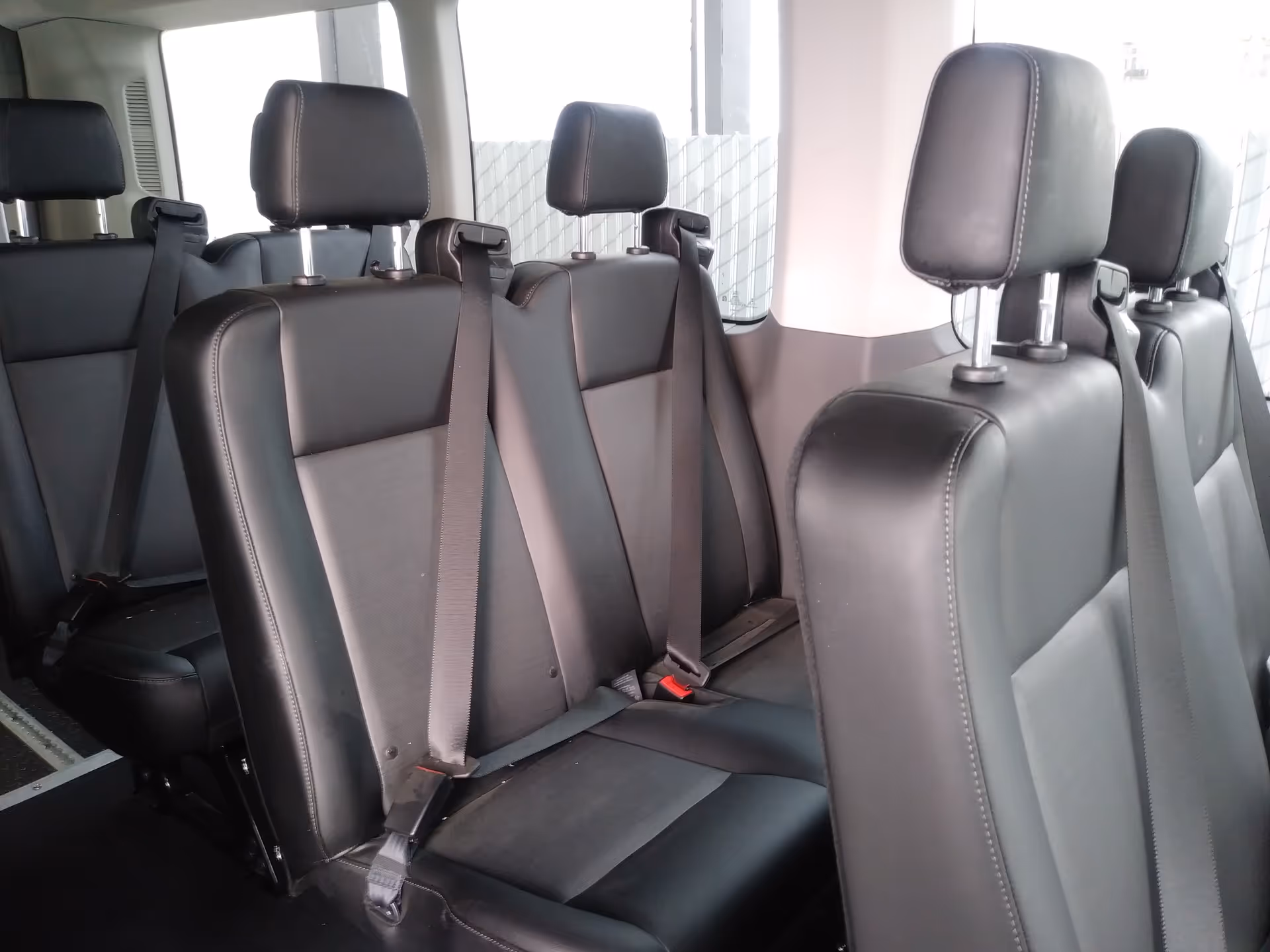 Inside a wheelchair-accessible van with multiple black leather seats and seat belts.