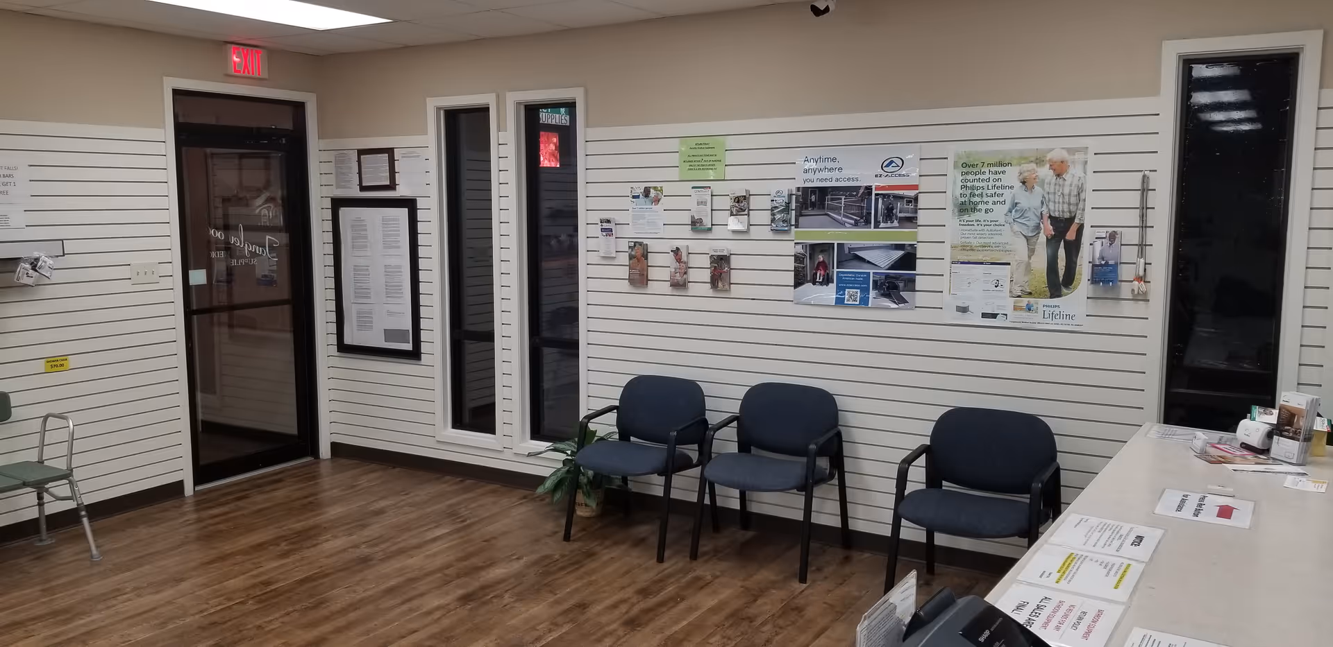 Interior lobby with four blue chairs, bulletin boards, and a reception desk along a paneled wall.