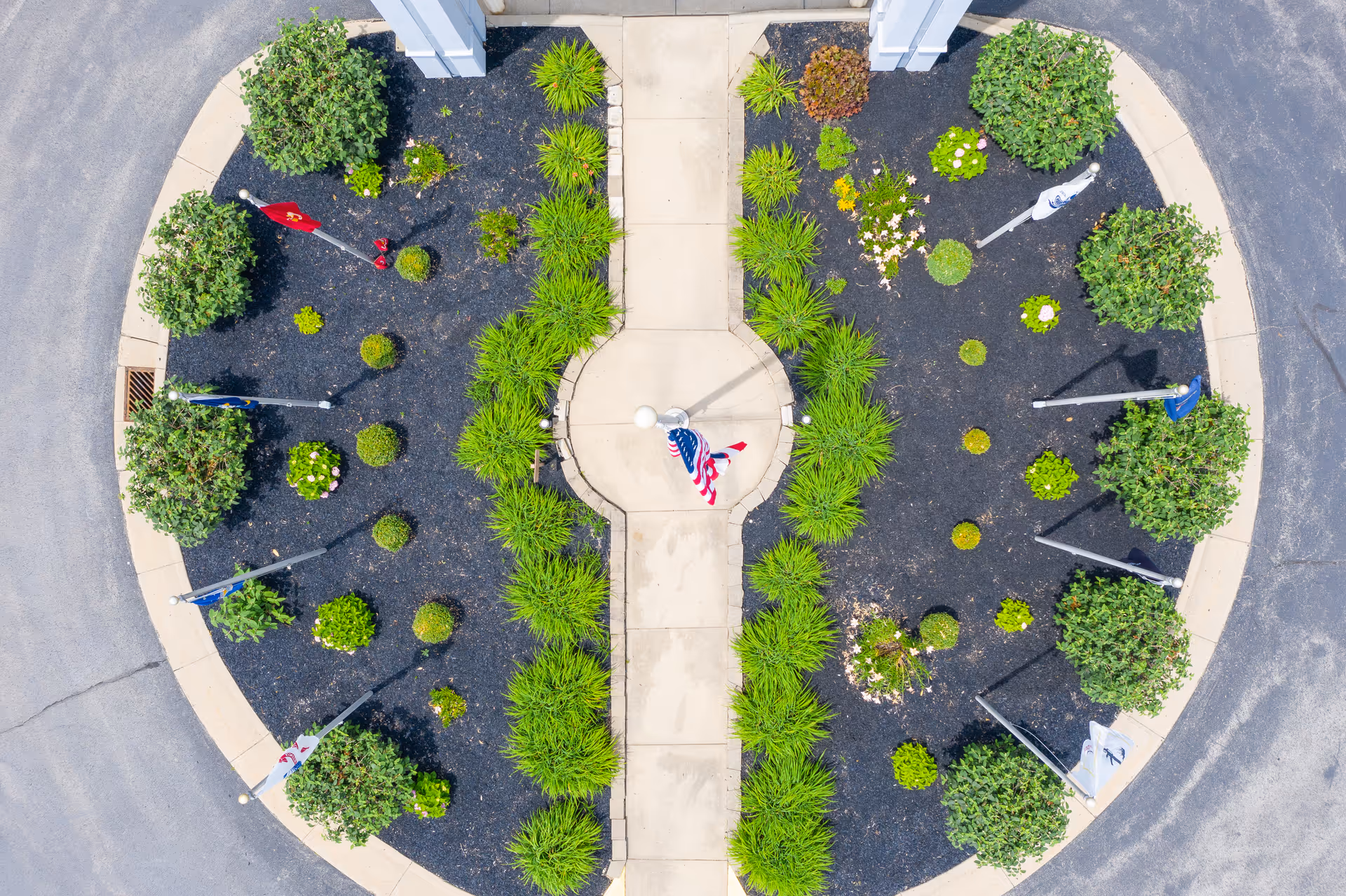Aerial view of a circular landscaped entrance with a central walkway and flags.