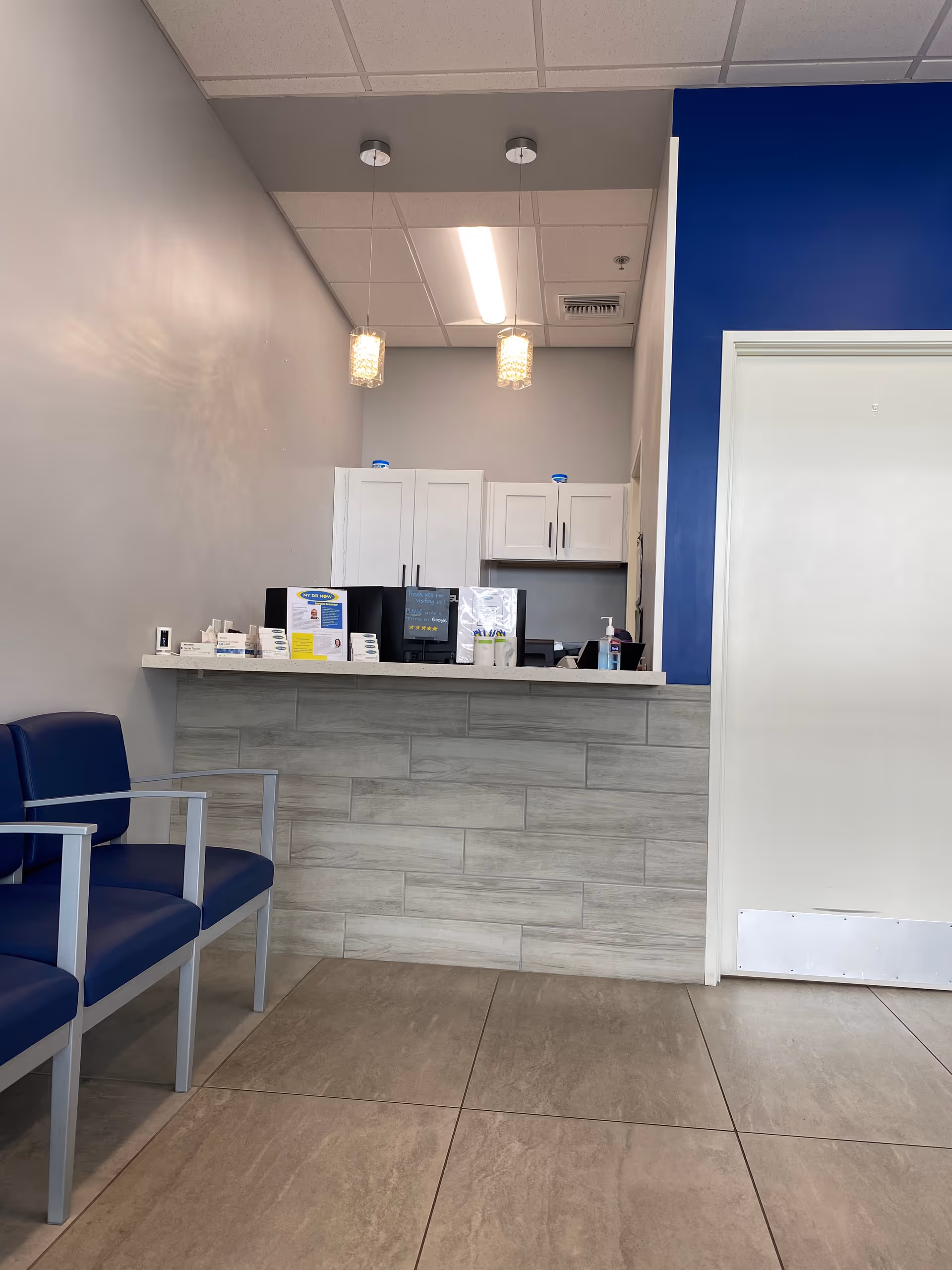 Interior reception area with a front desk, blue accents, and seating along the wall.