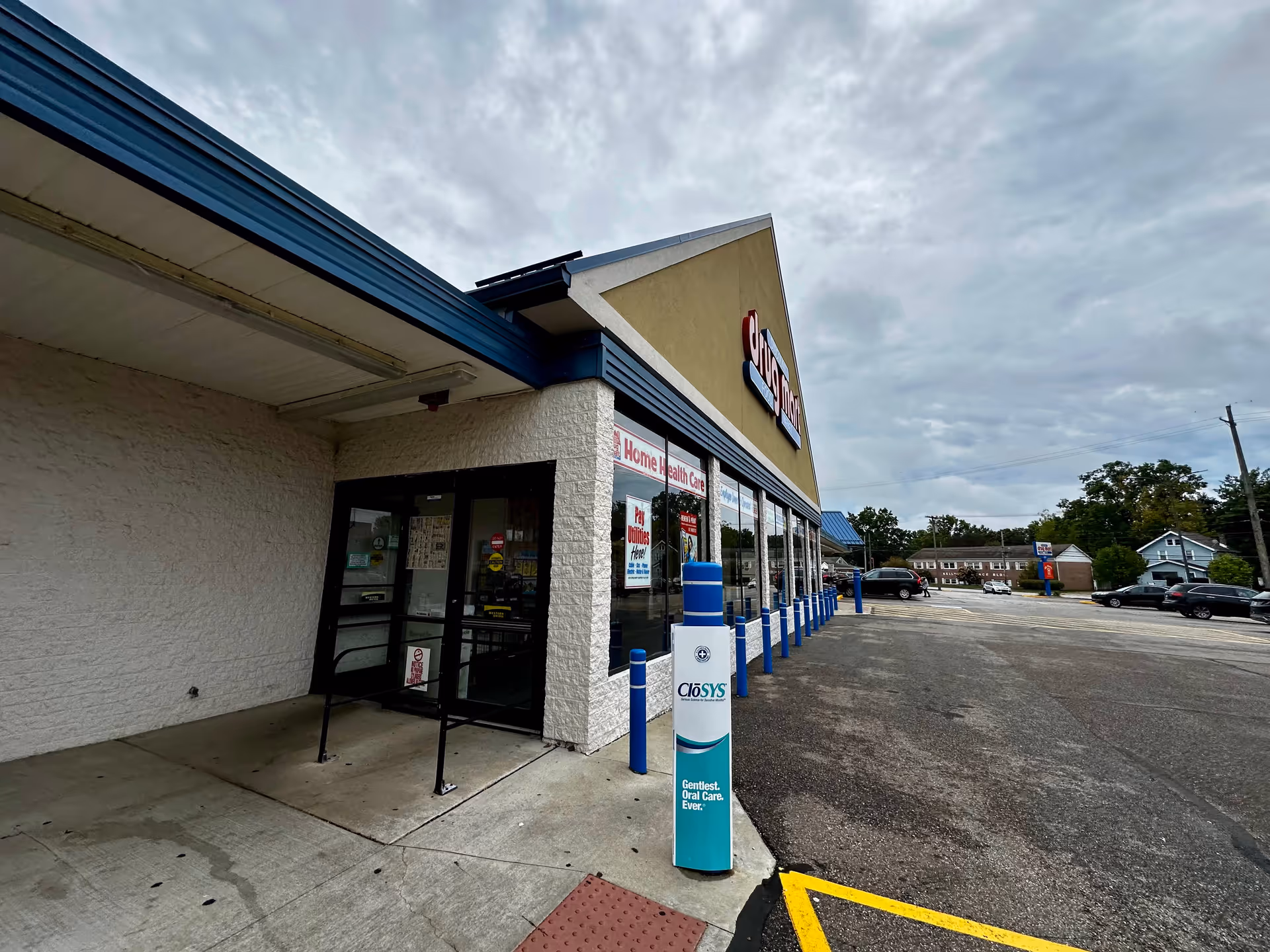 Exterior view of Discount Drug Mart storefront with blue awning and parking area